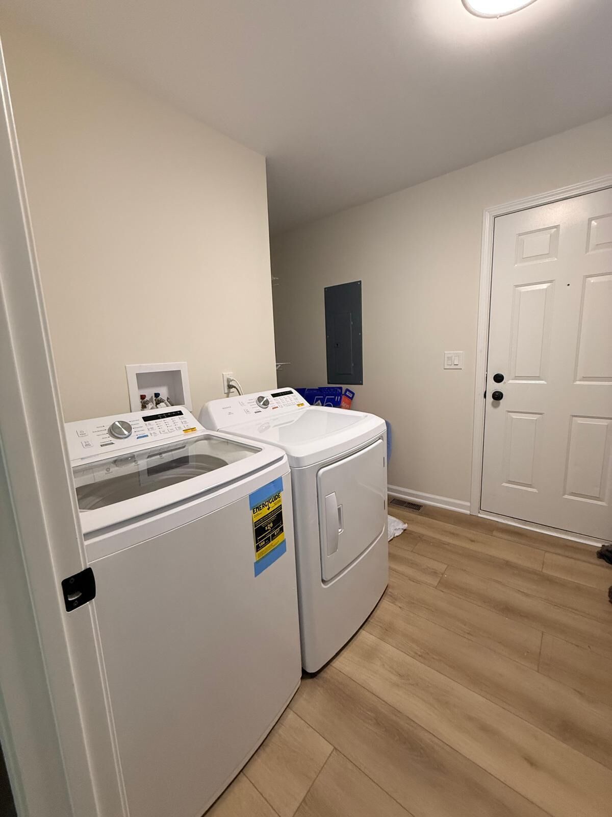 A laundry room with a washer and dryer, a small shelf with items, and a door.