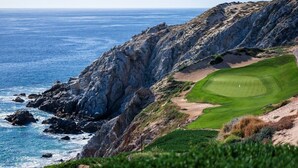 Ein Küsten-Golfplatz mit Felsen und dem Meer.