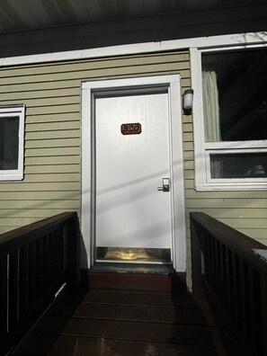 A front door with a number plate, a small window to the left, and a wooden staircase leading up to it. - Cozy 1BR hotel room, Hamilton - 320 Shenandoah (Hamilton)