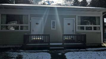 A single-story building with a front porch, two doors, and windows.