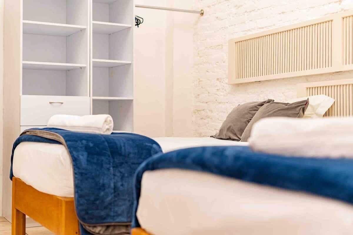 A bedroom with a bed, a wardrobe, and a white brick wall.