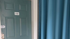 A teal door with a number plate, a doormat with 'Hello' text, and a blue curtain. - Secrets Under the Palms - Luxury 1BR King Condo, Pond View Lanai (Lutz)