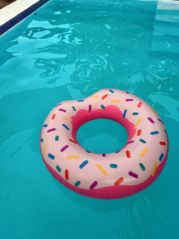A swimming pool with a pink donut float.