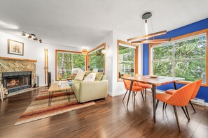 Ein modernes Wohnzimmer mit Kamin, Essbereich und großen Fenstern.