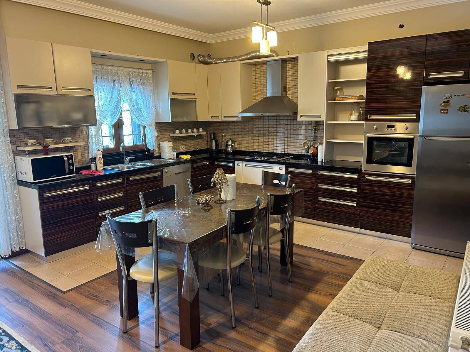 A modern kitchen with dark wood cabinets, stainless steel appliances, and a central island with chairs.