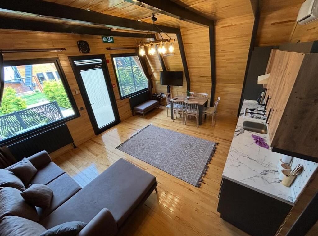 Interior acogedor de una cabaña con sofá, mesa de comedor y zona de cocina.