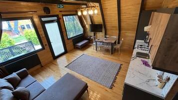 Interior acogedor de una cabaña con sofá, mesa de comedor y zona de cocina.