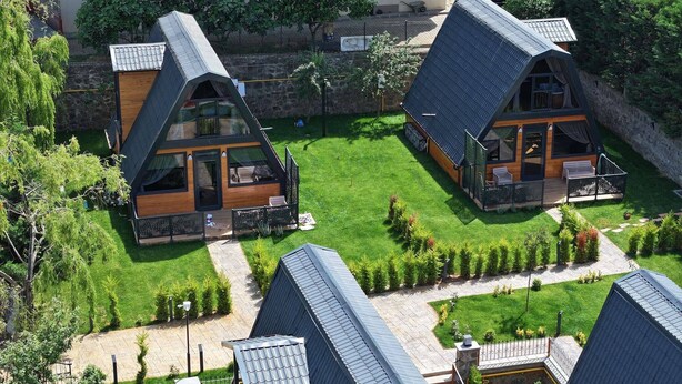 Una casa moderna de estilo cabaña con una terraza grande y un césped bien cuidado.