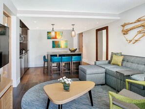 Een moderne woonkamer met een grijze modulaire bank, een ronde salontafel en een eethoek met blauwe stoelen.