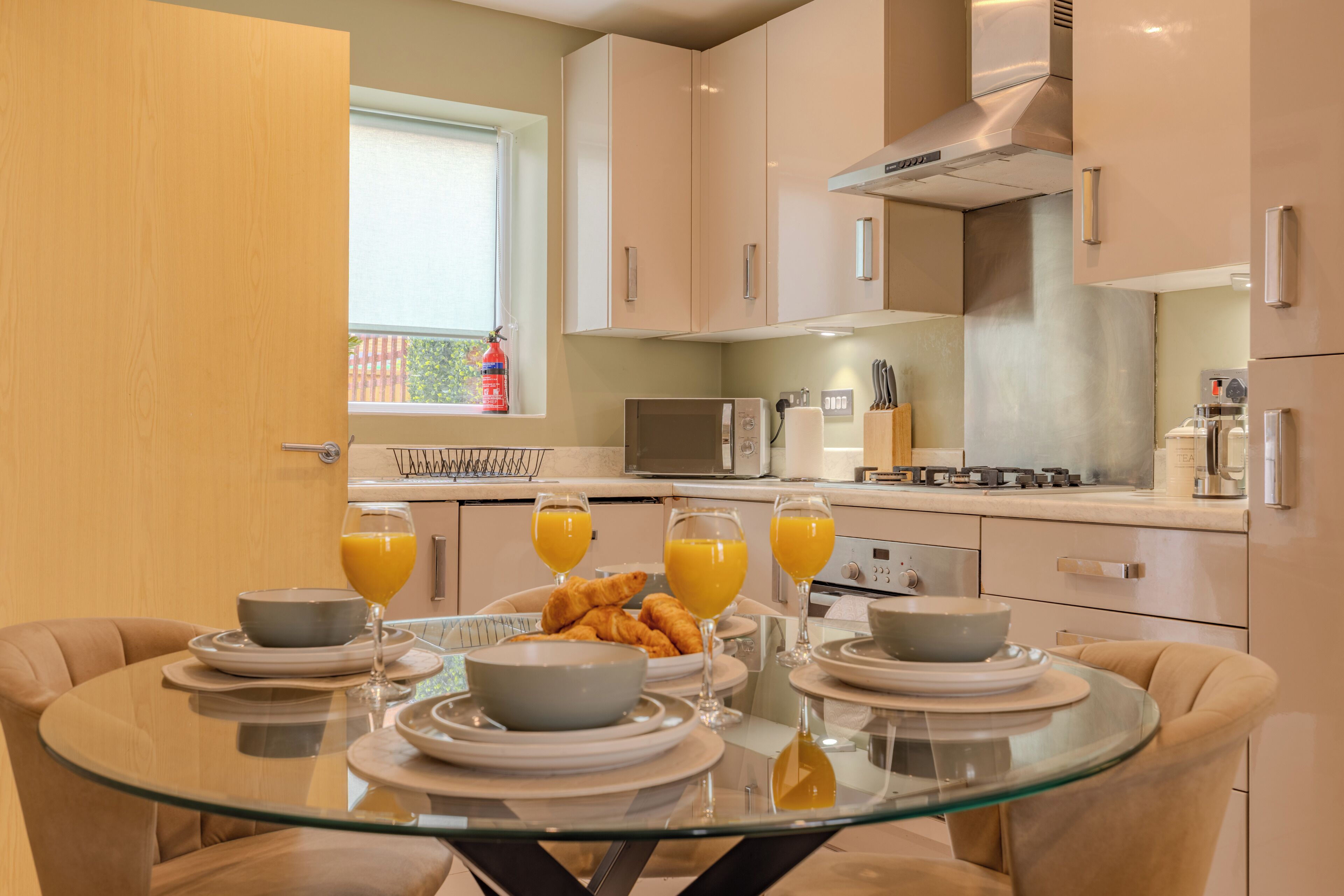 Eine moderne Küche mit einem Esstisch, gedeckt für das Frühstück, inklusive Croissants und Orangensaft.