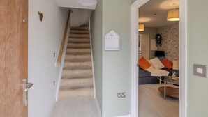 Escadaria que leva a uma sala de estar com sofá, mesa de centro e um objeto decorativo na parede.