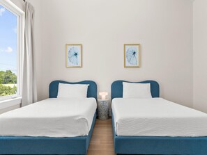 A room with two beds, a nightstand, and two framed wall art pieces. - 3000 Blue Lagoon C (Panama City Beach)