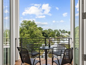 Een balkon met een tafel en stoelen, met uitzicht op een meer en bomen.