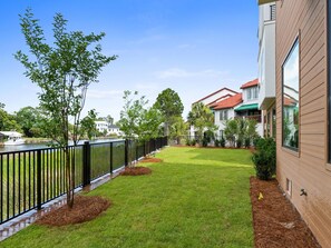 A residential area with a well-maintained lawn, a black metal fence, and houses with red-tiled roofs. - 3000 Blue Lagoon C (Panama City Beach)