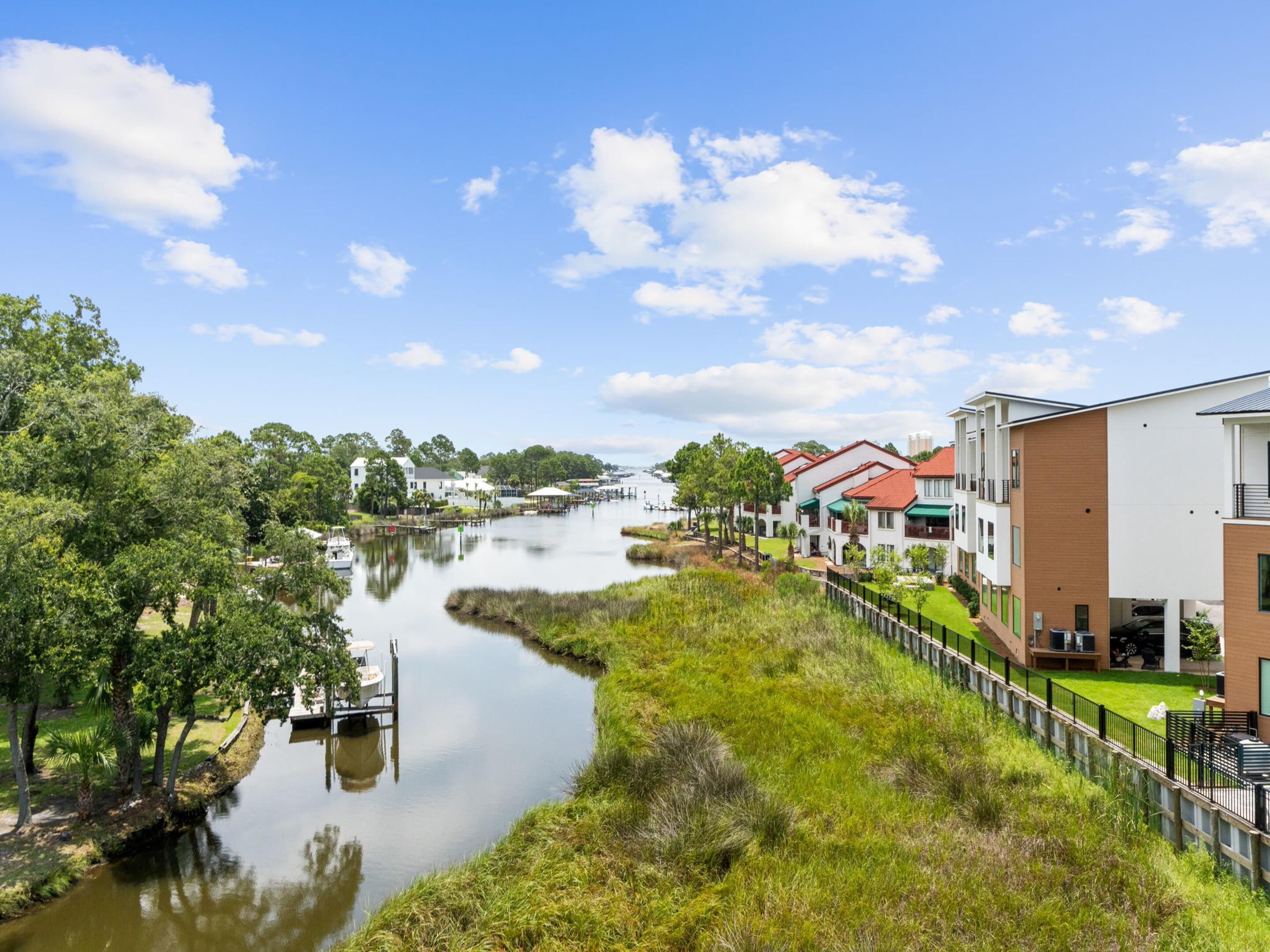 A riverside view with modern buildings, a dock, and lush greenery.