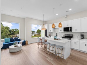 A modern kitchen with white cabinets, a central island, and bar stools. - 3000 Blue Lagoon C (Panama City Beach)