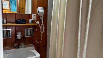 Un bagno con lavandino, specchio, asciugacapelli e tenda da doccia.