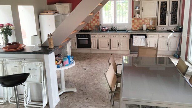 A kitchen with white cabinets, a dining table, and a staircase. - Family villa with a stunning view of the countryside, close to the beaches and marshes (Breuillet)