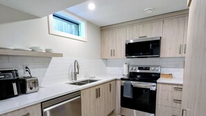 Une cuisine moderne équipée d’un lave-vaisselle, d’une cuisinière, d’un four à micro-ondes et de meubles de rangement en bois.