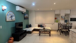 A living room with a sofa, TV, and a dining area with chairs and a table. - Your home by the Beach! 2bedroom penthouse apartment in Isla Verde, PR (Carolina)