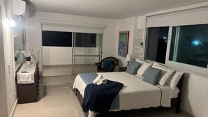 A bedroom with a bed, a chair, a small table, a window, and a door. - Your home by the Beach! 2bedroom penthouse apartment in Isla Verde, PR (Carolina)