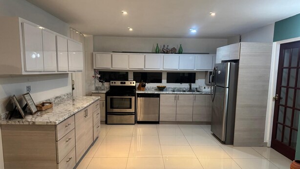 A modern kitchen with white cabinets, stainless steel appliances, and a tiled floor. - Your home by the Beach! 2bedroom penthouse apartment in Isla Verde, PR (Carolina)