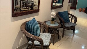 A room with two wicker chairs, a small round table, and two large mirrors on the wall. - Your home by the Beach! 2bedroom penthouse apartment in Isla Verde, PR (Carolina)