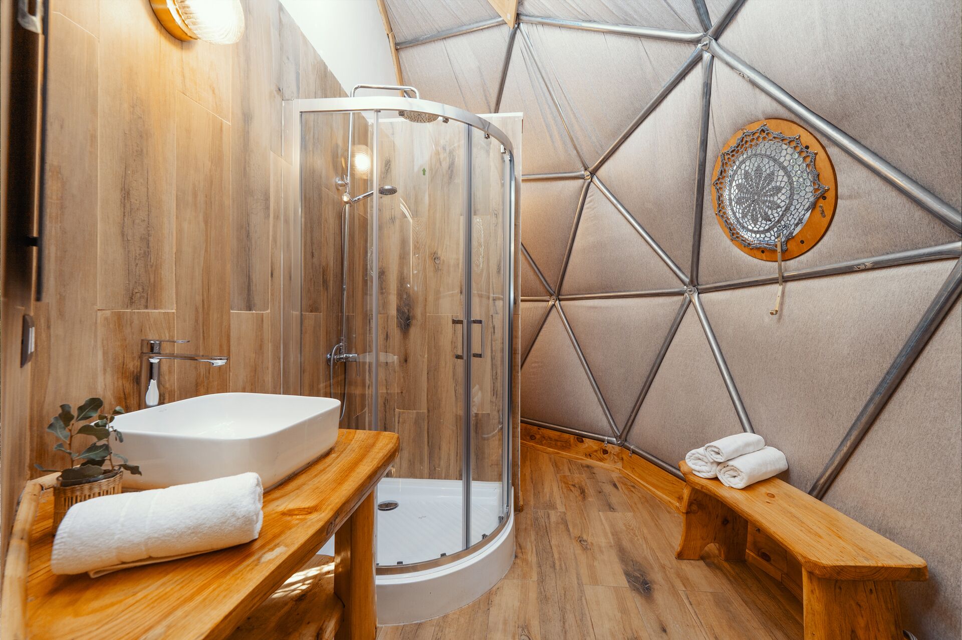 Une salle de bain moderne avec une douche à parois de verre, un meuble-lavabo en bois et un motif géométrique sur le mur.