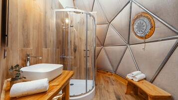 Une salle de bain moderne avec une douche à parois de verre, un meuble-lavabo en bois et un motif géométrique sur le mur.