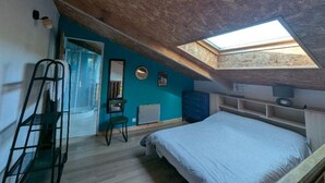 Een slaapkamer met dakraam, een bed, een stoel, een bureau en een kledingkast.