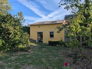 A yellow building with a door and windows, surrounded by greenery. - Vrbo Property (Cintré)