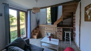 Een modern interieur met een bank, een klein tafeltje, een keuken met houten kastjes en een trap naar een hoger niveau.