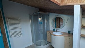 Een badkamer met een douchecabine van glas, een wastafel met spiegel en een handdoekrek.