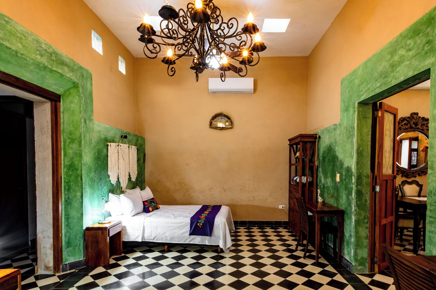 Quarto com cama, lustre, espelho e piso xadrez.