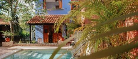 A pool area with a building in the background, surrounded by palm trees.
