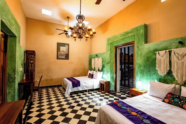 A room with two beds, a chandelier, a checkered floor, and a green accent wall.