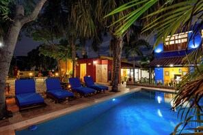 A pool area with lounge chairs and a building with illuminated windows.