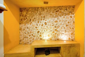 A stone wall with a wooden bench and a small shelf.