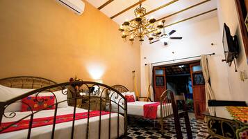 A room with two beds, a chandelier, a ceiling fan, and a checkered floor.