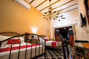 A room with two beds, a chandelier, a ceiling fan, and a checkered floor. - Casa Vicenta (Izamal)