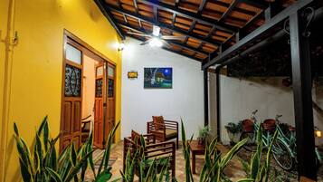 A room with a yellow wall, wooden furniture, a ceiling fan, and a painting.