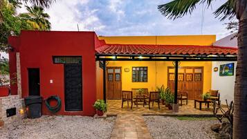 A two-story building with a red and yellow facade, a tiled roof, and a patio area with outdoor seating.