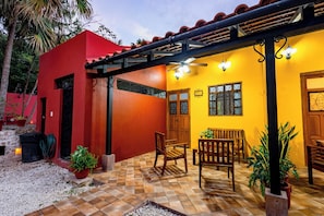 Un patio con un edificio rojo, una pared amarilla y un piso de baldosas.