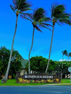 A sign for Poipui Kai Resort with palm trees and a stone wall. - Ocean Views • Dual Lanais & A/C • Walk to Beaches, Pools & Tennis @ BluEscape (Koloa)