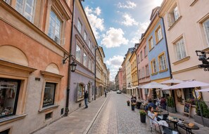 A cobblestone street lined with historic buildings, outdoor seating at cafes, and a clear blue sky. - MYE Apartments - Fancy Bicycle Apartment - Old City, FV (Warszawa)