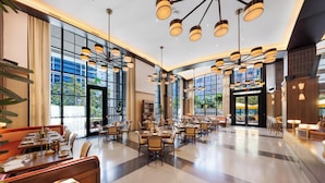 A spacious hotel dining area with multiple tables and chairs, large windows, and modern lighting fixtures. - Luxury Miami 1BR - 25th Fl - Pool & Gym (Miami)