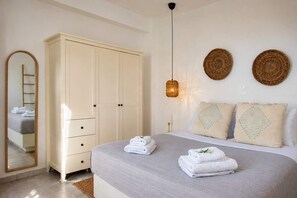 Ein Schlafzimmer mit einem Bett, einem Kleiderschrank, einem Spiegel und zwei gewebten Wandbildern.