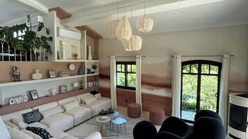 Un salon moderne avec un canapé, des fauteuils noirs, une table basse et une cheminée.