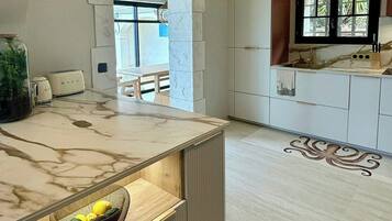 Une cuisine moderne dotée de plans de travail en marbre, d’un îlot central intégré et donnant sur l’espace repas.