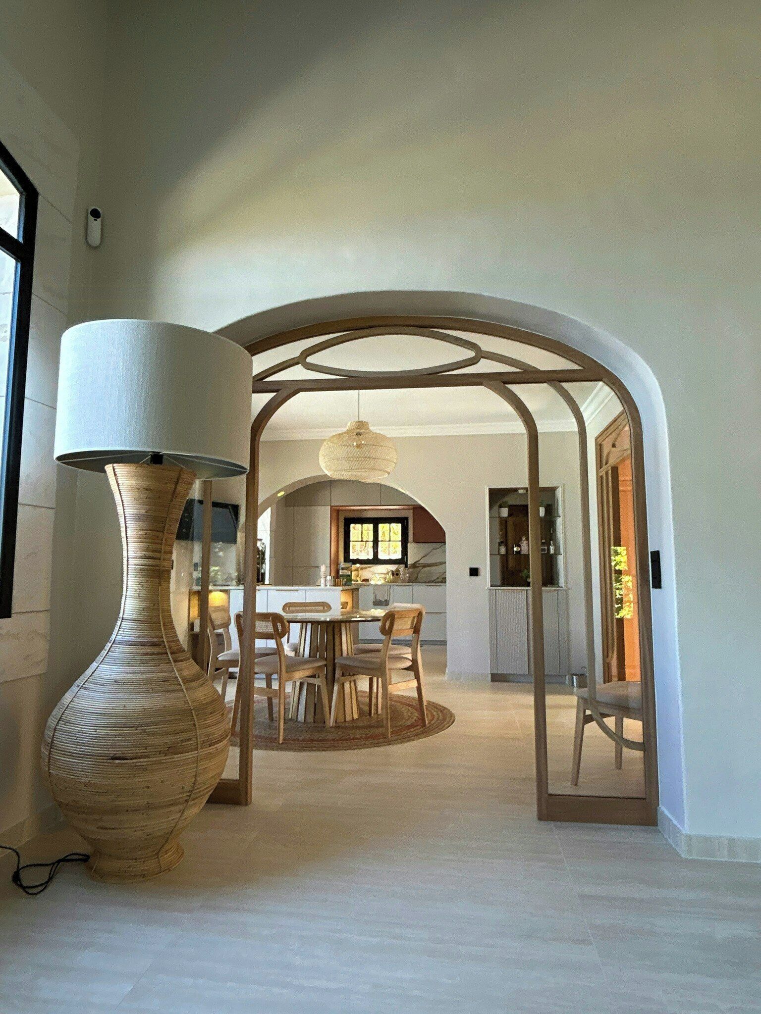 Un intérieur comprenant un coin repas, un grand vase et une cuisine en arrière-plan.